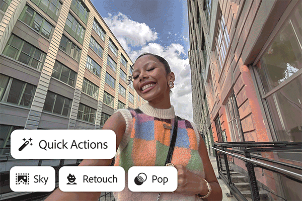 Young woman smiling and taking a selfie outdoors between tall buildings on a partly cloudy day.