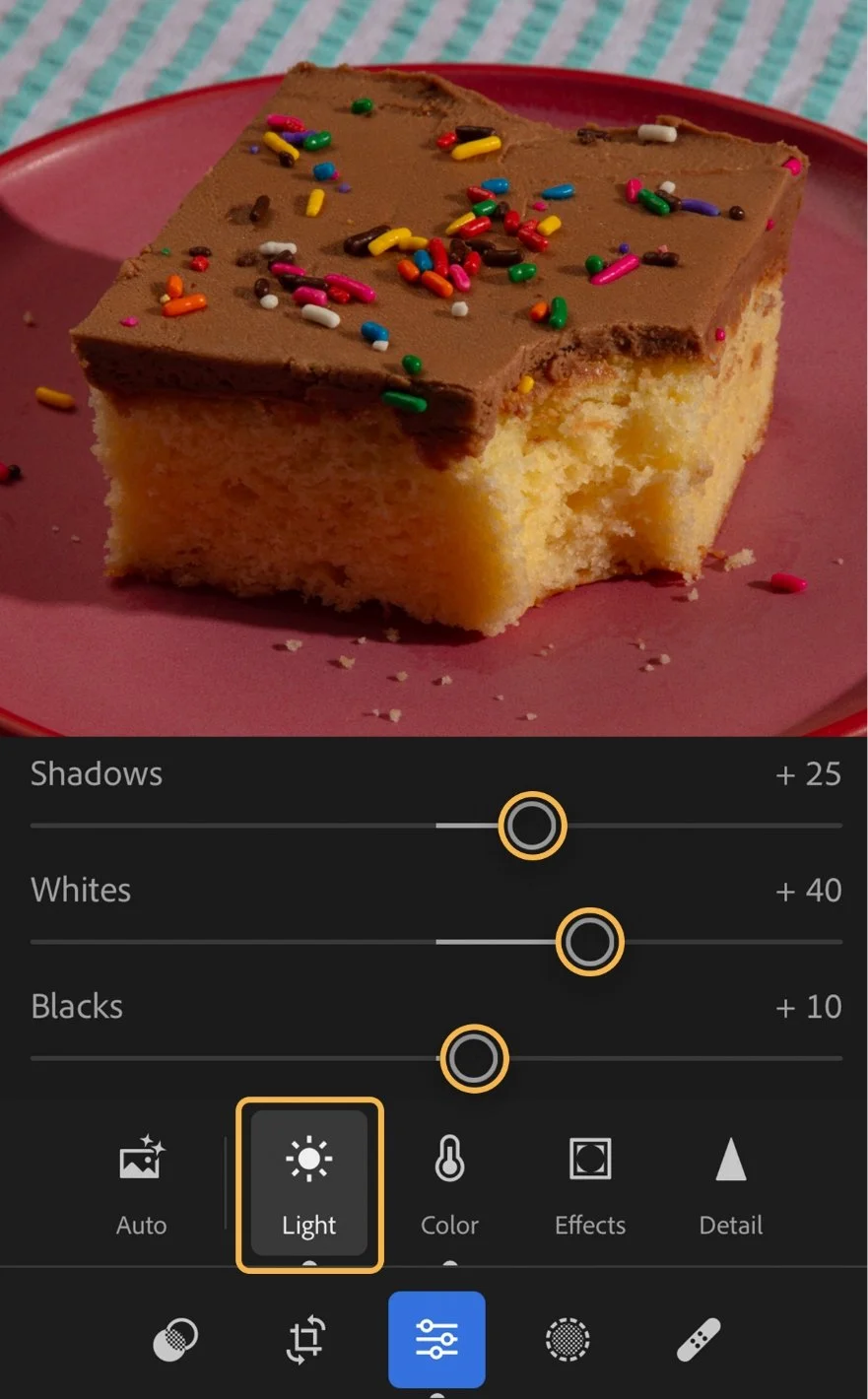 A square piece of vanilla cake with chocolate frosting topped with colorful sprinkles on a pink plate. Showing feature UI.